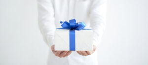 Un hombre sosteniendo una caja de regalo con un lazo azul