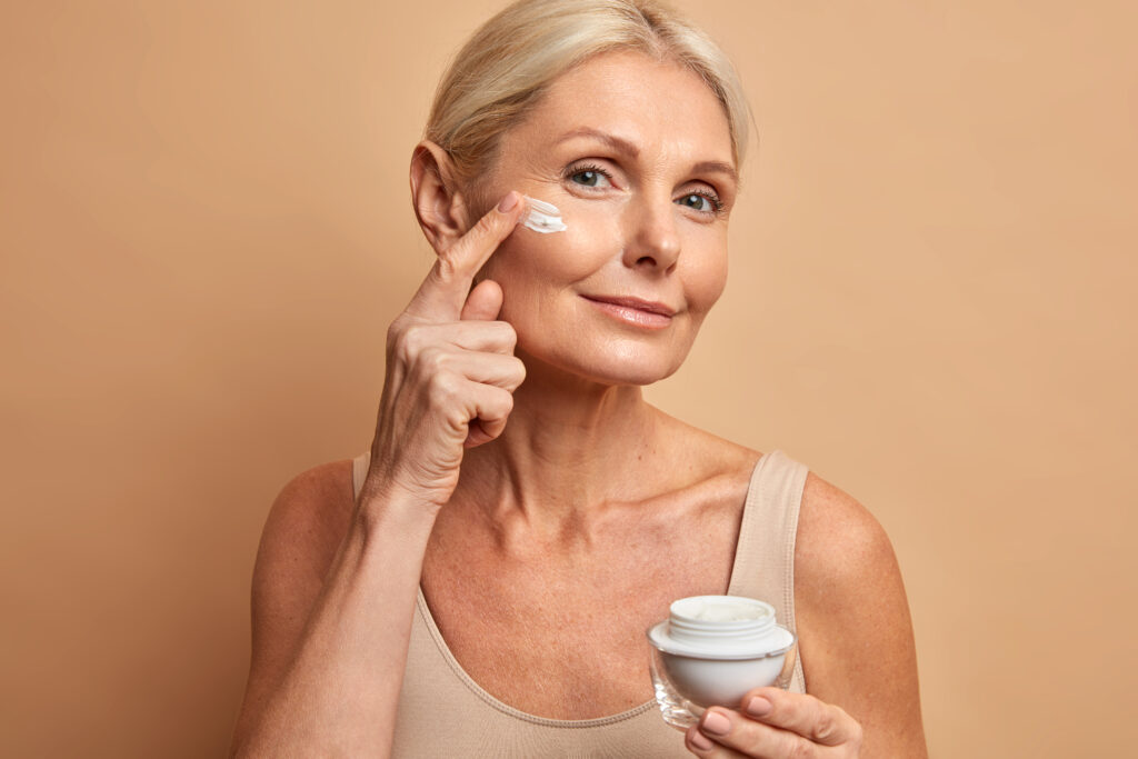 hermosa mujer mediana edad aplica crema antienvejecimiento cara somete tratamientos belleza preocupa piel