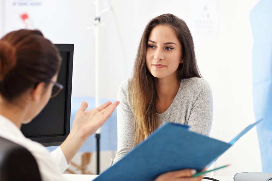 Paciente joven en consulta médica, evaluando opciones de cirugía íntima femenina junto a una profesional de la salud.