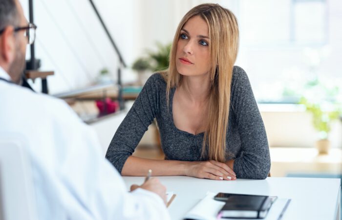Mujer interesada en una consulta médica sobre liposucción y reducción de monte de Venus, valorando beneficios y opciones del procedimiento.