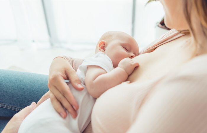Mujer con su bebé en brazos amamantando con implantes tras un aumento de pecho realizado mediante cirugía estética.