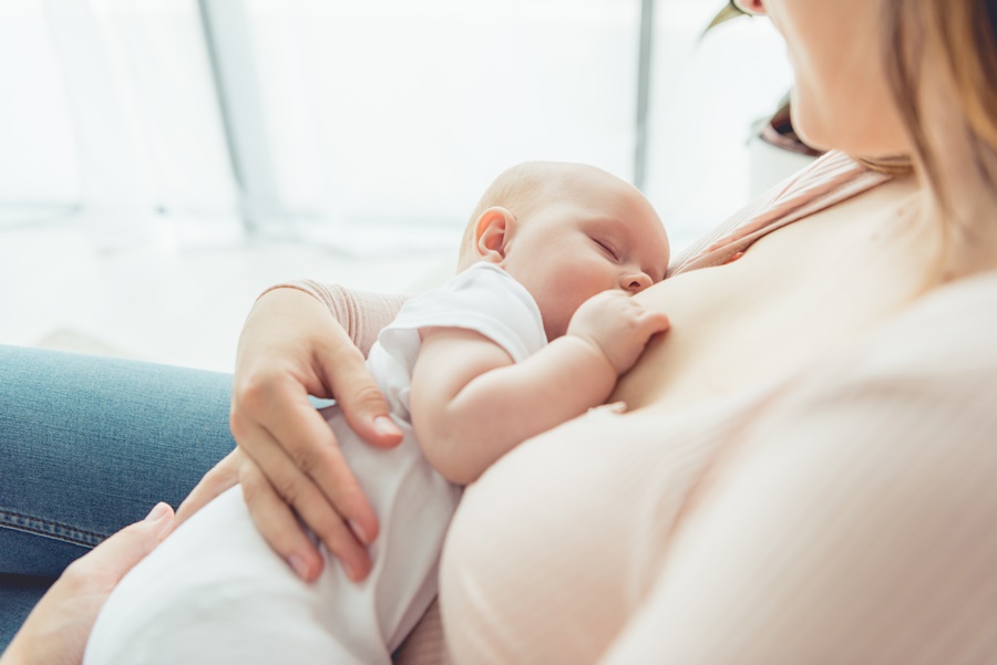 Mujer con su bebé en brazos amamantando con implantes tras un aumento de pecho realizado mediante cirugía estética.