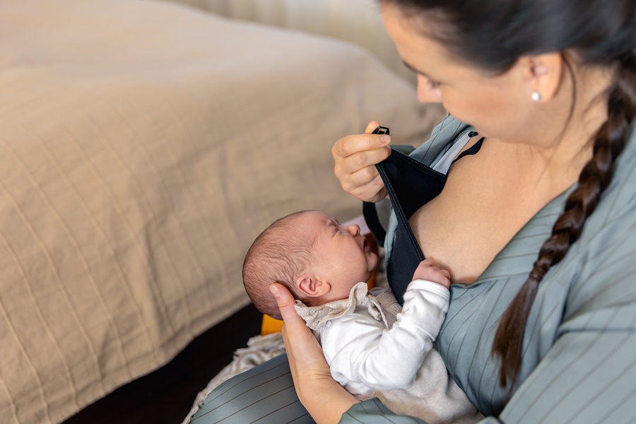 Madre preparándose para dar el pecho a su hijo tras un aumento de pecho con implantes y cirugía estética.
