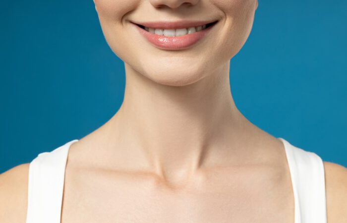 Primer plano del mentón de una mujer con sonrisa simétrica, ilustrando el resultado estético tras una mentoplastia de aumento con implantes vs. lipotransferencia.