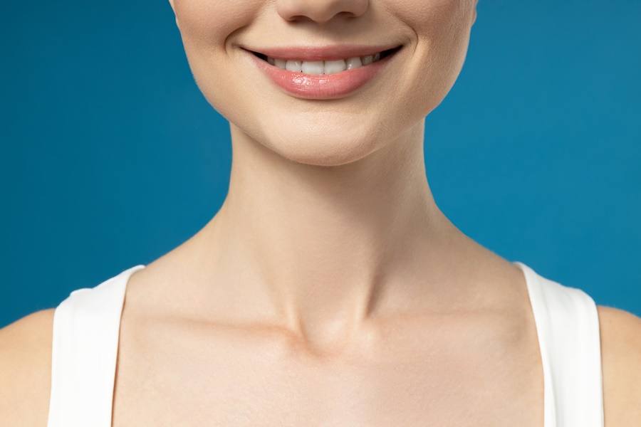 Primer plano del mentón de una mujer con sonrisa simétrica, ilustrando el resultado estético tras una mentoplastia de aumento con implantes vs. lipotransferencia.