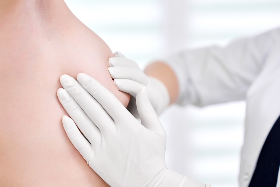 Médico realizando exploración física del pecho de una paciente para diagnosticar y planificar el tratamiento de pezones invertidos.