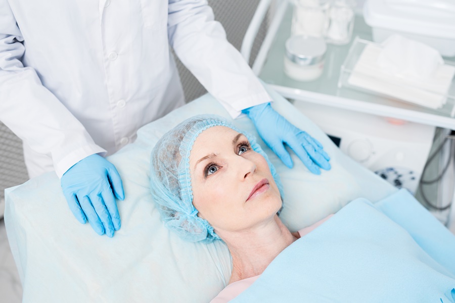 Paciente en camilla de clínica estética, lista para intervención, en contexto de evaluación de factores hormonales y cirugía estética personalizada.