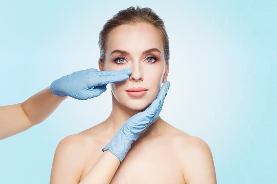 Mujer joven de rostro simétrico siendo evaluada por un profesional médico en una consulta previa a una rinoplastia ultrasónica, técnica enfocada en mejorar la armonía facial sin dañar tejidos blandos.