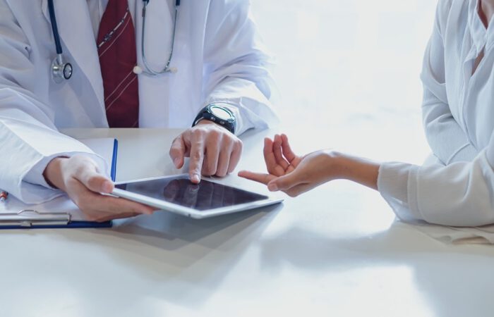 Consulta médica sobre cirugía plástica, donde un profesional analiza con una paciente los posibles resultados utilizando una tablet. La imagen ilustra el uso de tecnología para visualizar resultados de cirugía plástica antes de la intervención.