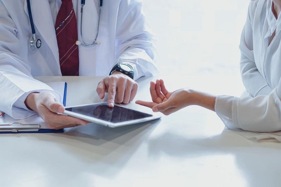 Consulta médica sobre cirugía plástica, donde un profesional analiza con una paciente los posibles resultados utilizando una tablet. La imagen ilustra el uso de tecnología para visualizar resultados de cirugía plástica antes de la intervención.