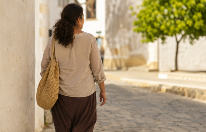 Mujer adulta paseando con calma en un entorno exterior luminoso, de tres cuartos. Imagen ilustrativa.