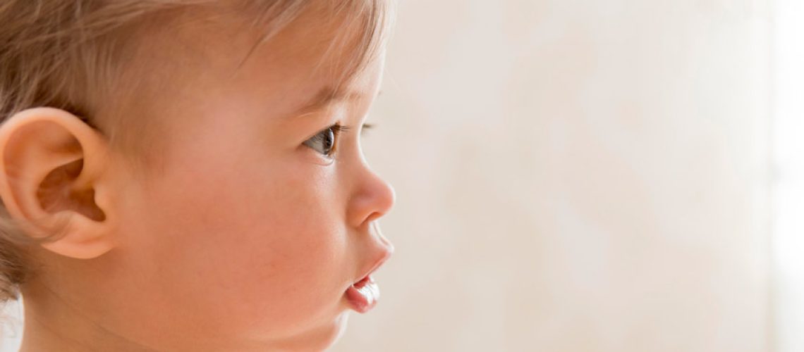 Primer plano de una niña con orejas prominentes mirando hacia el lado. Otoplastia en niños